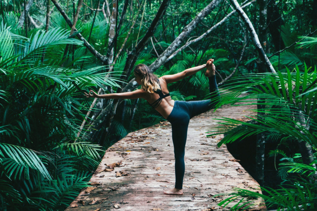 Young woman doing yoga in the tropical forest